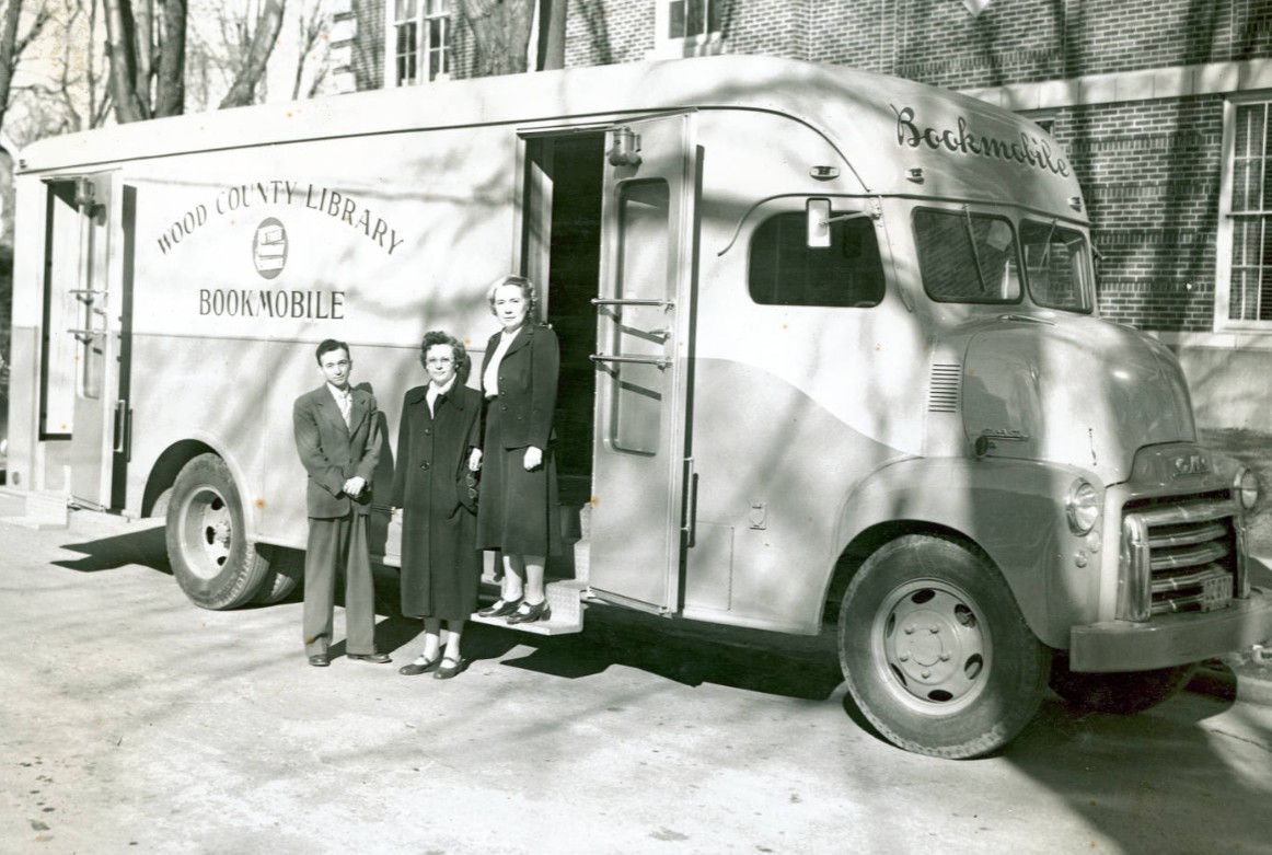 The first bookmobile with three librarians on its steps.