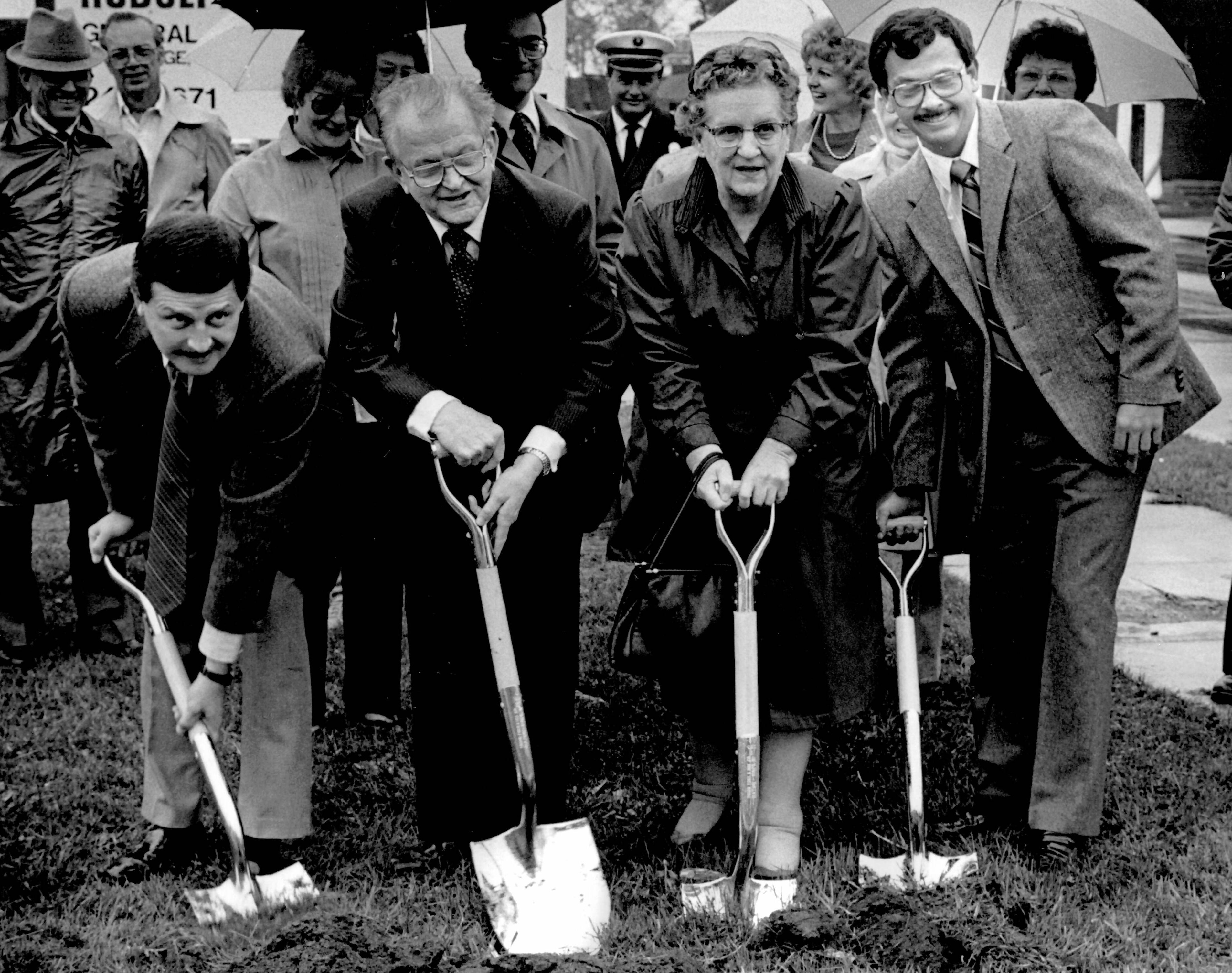 Four people with shovels breaking ground for the library.