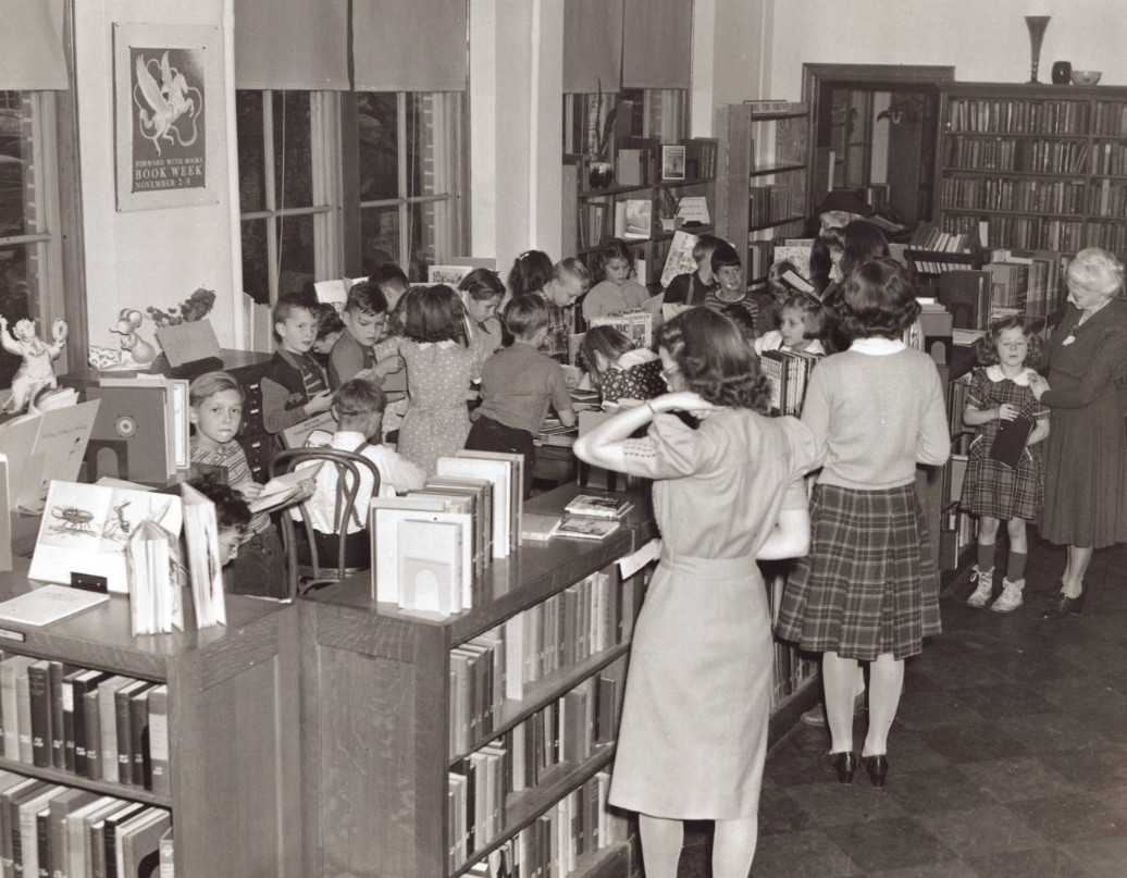 The high school library in 1928, with students browsing stacks of books.